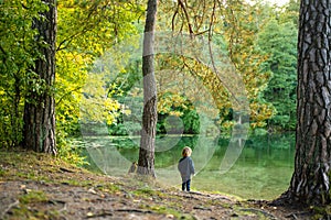 Adorable toddler boy admiring the Balsys lake, one of six Green Lakes, located in Verkiai Regional Park. Child exploring nature on