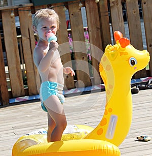 Adorable Toddler Boy eating a popsicle by the Pool