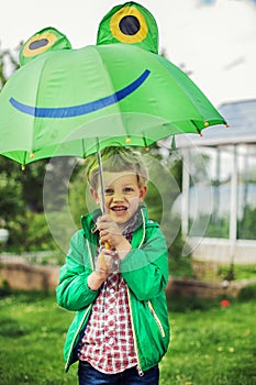 Adorable toddler boy with green frog umbrella