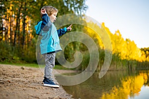 Adorable toddler boy having fun by the Gela lake on sunny fall day. Child exploring nature on autumn day in Vilnius, Lithuania