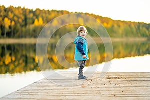 Adorable toddler boy having fun by the Gela lake on sunny fall day. Child exploring nature on autumn day in Vilnius, Lithuania