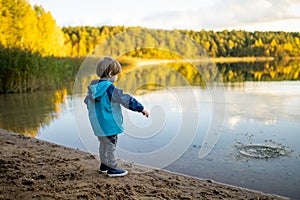 Adorable toddler boy having fun by the Gela lake on sunny fall day. Child exploring nature on autumn day in Vilnius, Lithuania