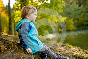 Adorable toddler boy having fun by the Gela lake on sunny fall day. Child exploring nature on autumn day in Vilnius, Lithuania