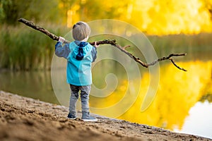 Adorable toddler boy having fun by the Gela lake on sunny fall day. Child exploring nature on autumn day in Vilnius, Lithuania