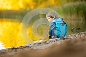 Adorable toddler boy having fun by the Gela lake on sunny fall day. Child exploring nature on autumn day in Vilnius, Lithuania