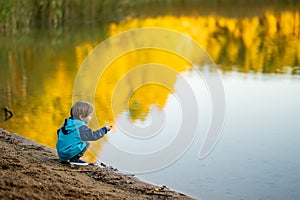 Adorable toddler boy having fun by the Gela lake on sunny fall day. Child exploring nature on autumn day in Vilnius, Lithuania