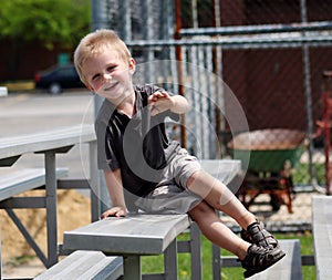 Adorable Toddler Boy sitting on the bleachers at a baseball game