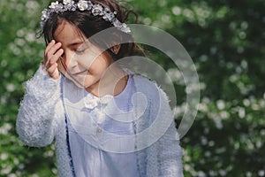 Adorable toddler child girl in light blue dressy outfit walking and playing in blooming spring garden