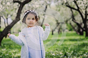 Adorable toddler child girl in light blue dressy outfit walking and playing in blooming spring garden photo