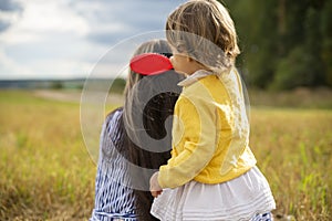 Adorable toddler girl combing her mom`s hair outdoors outdoors on a sunny day