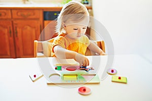 Adorable toddler girl doing wooden puzzle