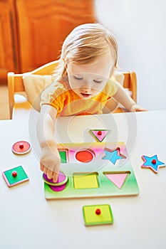 Adorable toddler girl doing wooden puzzle