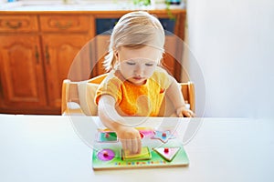 Adorable toddler girl doing wooden puzzle