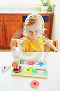 Adorable toddler girl doing wooden puzzle