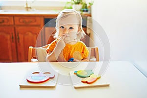 Adorable toddler girl doing wooden puzzle