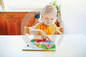 Adorable toddler girl doing wooden puzzle