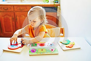 Adorable toddler girl doing wooden puzzle