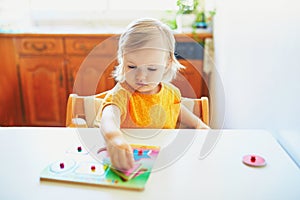 Adorable toddler girl doing wooden puzzle