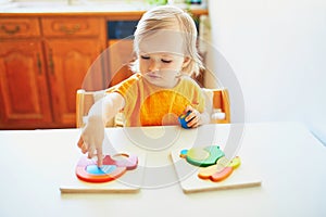 Adorable toddler girl doing wooden puzzle