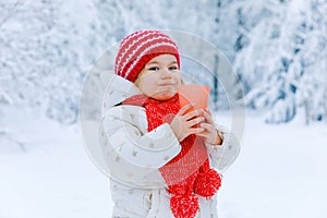 Adorable toddler girl drinking hot chocolate in winter forest. Happy healthy child with cup of steaming cocoa or tea