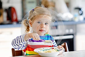 Adorable toddler girl eating healthy chicken noodle soup for lunch. Cute happy baby child taking food at home or nursery