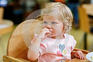 Adorable toddler girl eating healthy vegetables and unhealthy french fries potatoes. Cute happy baby child taking food