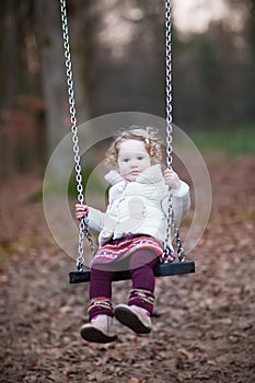 Adorable toddler girl having fun on a swing