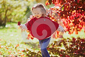 Adorable toddler girl playing in autumn park