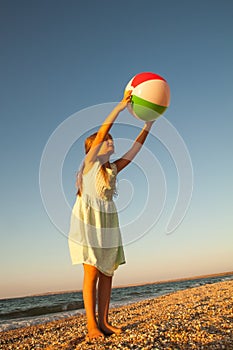 Adorable toddler girl playing ball on sand beach