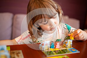 Adorable toddler girl playing board game indoors