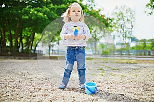Adorable toddler girl playing with bucket and shovel