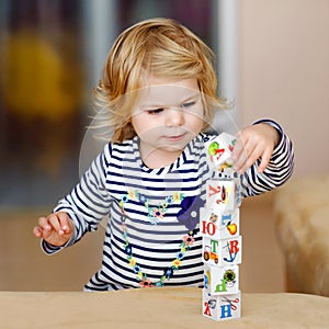 Adorable toddler girl playing with educational toys in nursery. Happy healthy child having fun with colorful different