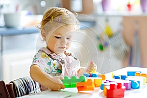 Adorable toddler girl playing with educational toys in nursery. Happy healthy child having fun with colorful different