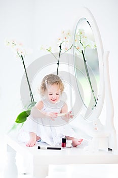 Adorable toddler girl playing with make up and cosmetics