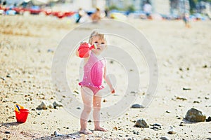 Adorable toddler girl playing with sand on the beach