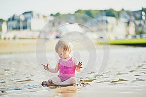 Adorable toddler girl playing with sand on the beach