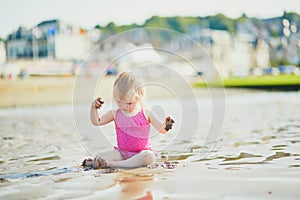 Adorable toddler girl playing with sand on the beach