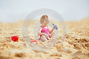Adorable toddler girl playing with sand on the beach