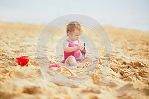 Adorable toddler girl playing with sand on the beach