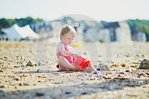 Adorable toddler girl playing with sand on the beach