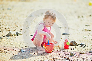 Adorable toddler girl playing with sand on the beach