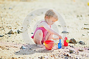 Adorable toddler girl playing with sand on the beach