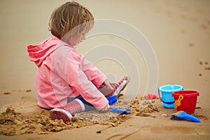 Adorable toddler girl playing on the sand beach at Atlantic coast