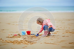 Adorable toddler girl playing on the sand beach at Atlantic coast