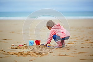 Adorable toddler girl playing on the sand beach at Atlantic coast