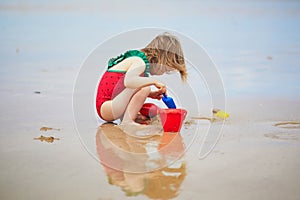 Adorable toddler girl playing on the sand beach at Atlantic coast of Brittany, France