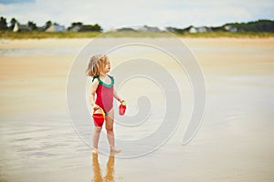 Adorable toddler girl playing on the sand beach at Atlantic coast of Brittany, France