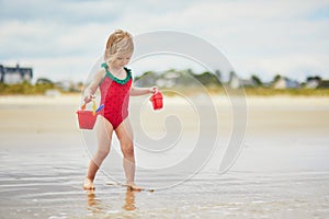 Adorable toddler girl playing on the sand beach at Atlantic coast of Brittany, France