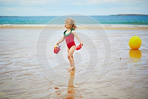Adorable toddler girl playing on the sand beach at Atlantic coast of Brittany, France