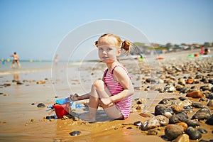 Adorable toddler girl playing on the sand beach at Atlantic coast of Brittany, France